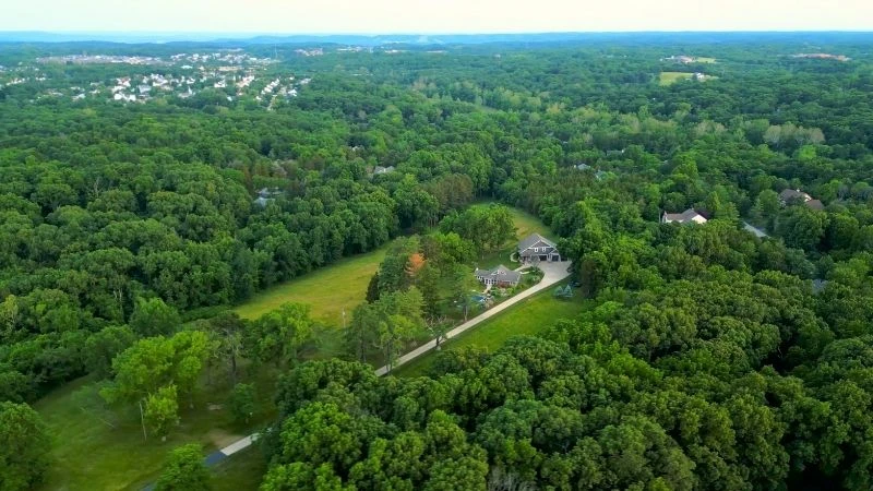 Aerial view of a wooded rural property with open pasture in Wildwood, Missouri