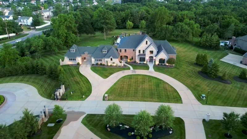 Aerial view of a luxury custom home with a circular drive on a large wooded lot in Wildwood
