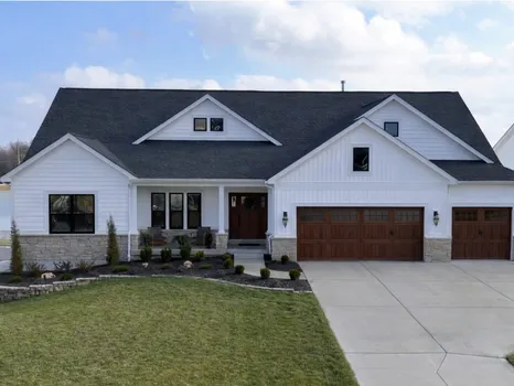 102 Royal Troon — white craftsman ranch with wood-toned garage doors overlooking a lake