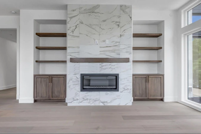 A condo interior with a floor-to-ceiling marble fireplace surround flanked by built-in shelving