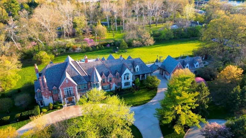 Aerial view of a large custom brick-and-stone mansion on a wooded Ladue estate lot