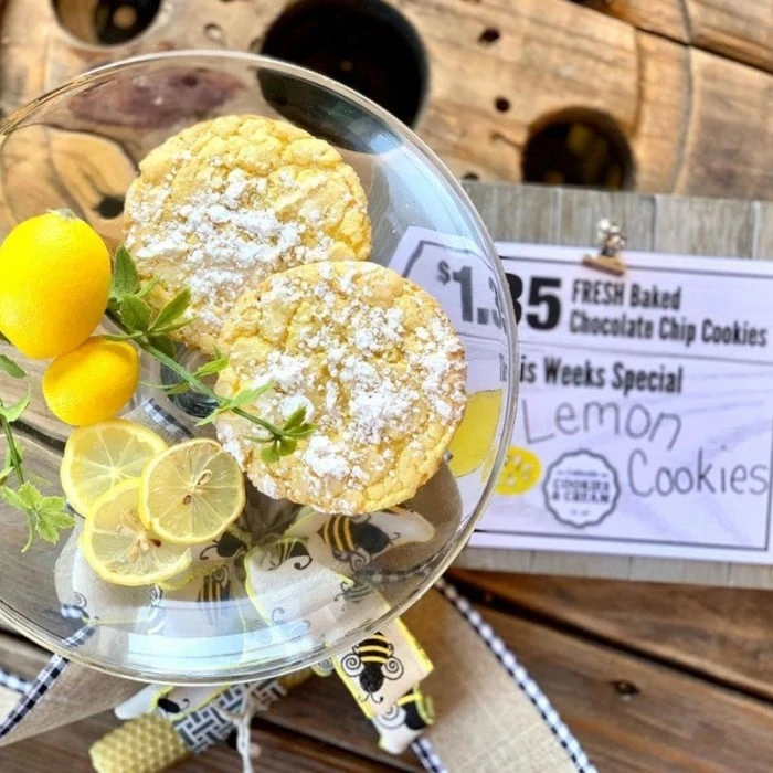 Lemon cookies dusted with powdered sugar beside a chalkboard special at Cottleville Cookies and Cream