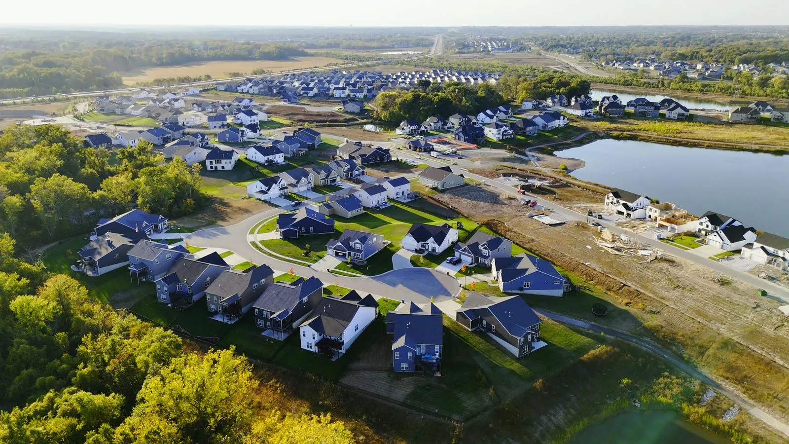 Wide aerial photograph of Cottleville Trails in October 2025 showing homes around a cul-de-sac with one of the lakes and wooded ground behind