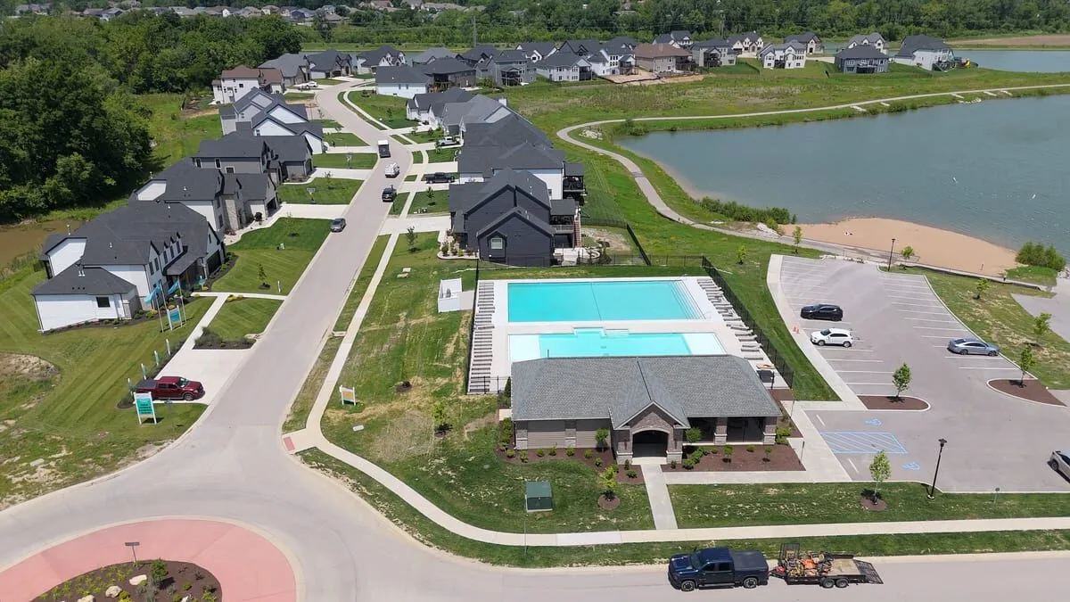 Aerial view of finished homes, the community pool and pool house, and the lake at Cottleville Trails