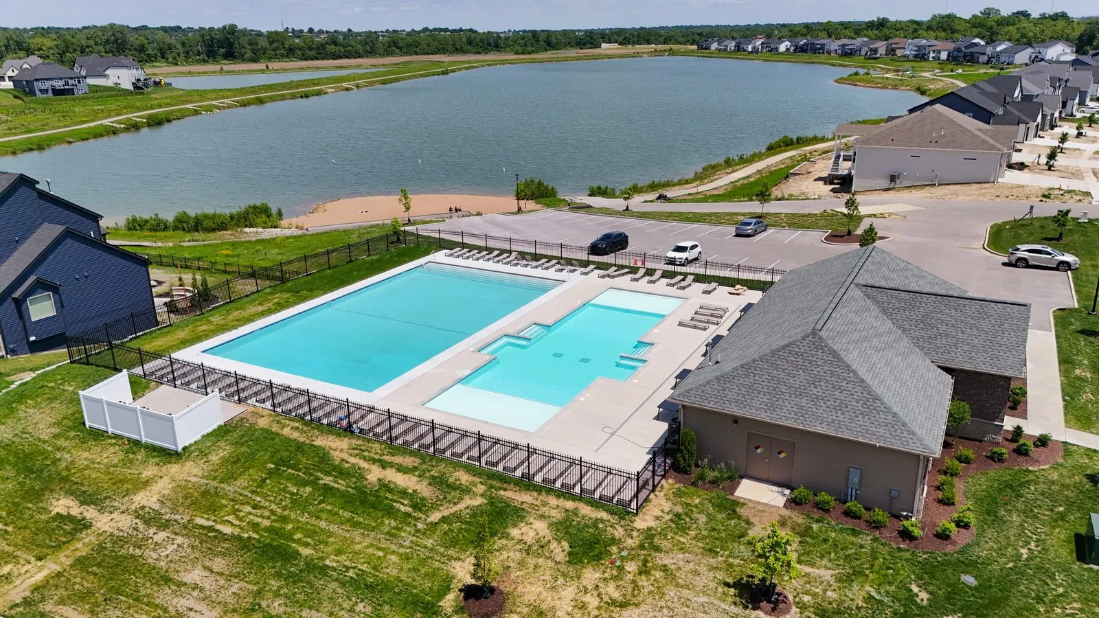 Aerial photograph of the Cottleville Trails community pool and pool house, with lounge chairs along the deck and one of the lakes directly behind
