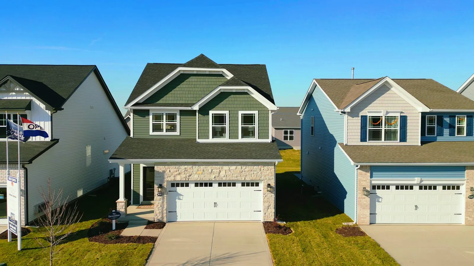 Two of the first Fischer & Frichtel homes completed at Cottleville Trails, a green home and a light blue home side by side in December 2023