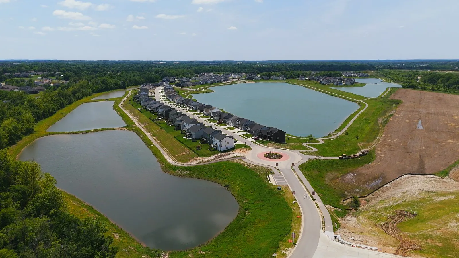 Aerial photograph of Cottleville Trails in May 2026 showing homes between two of the community lakes, with graded ground awaiting the final phase on the right