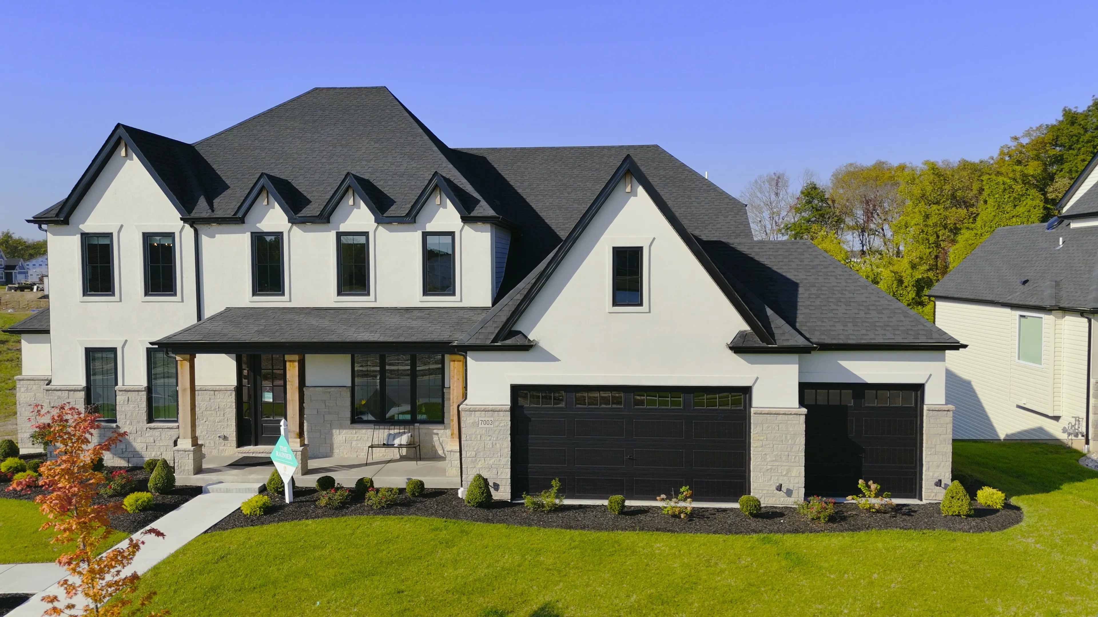 A white and black two-story display home built by Lombardo Homes at Cottleville Trails, photographed from the street on an autumn afternoon