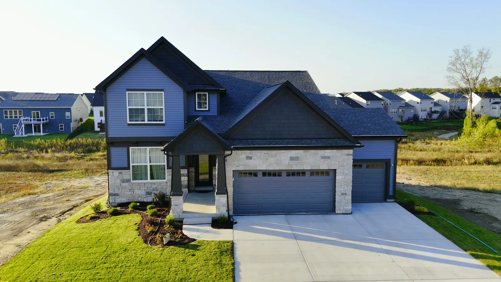 A navy blue two-story home at Cottleville Trails built by McKelvey Homes, photographed from the driveway