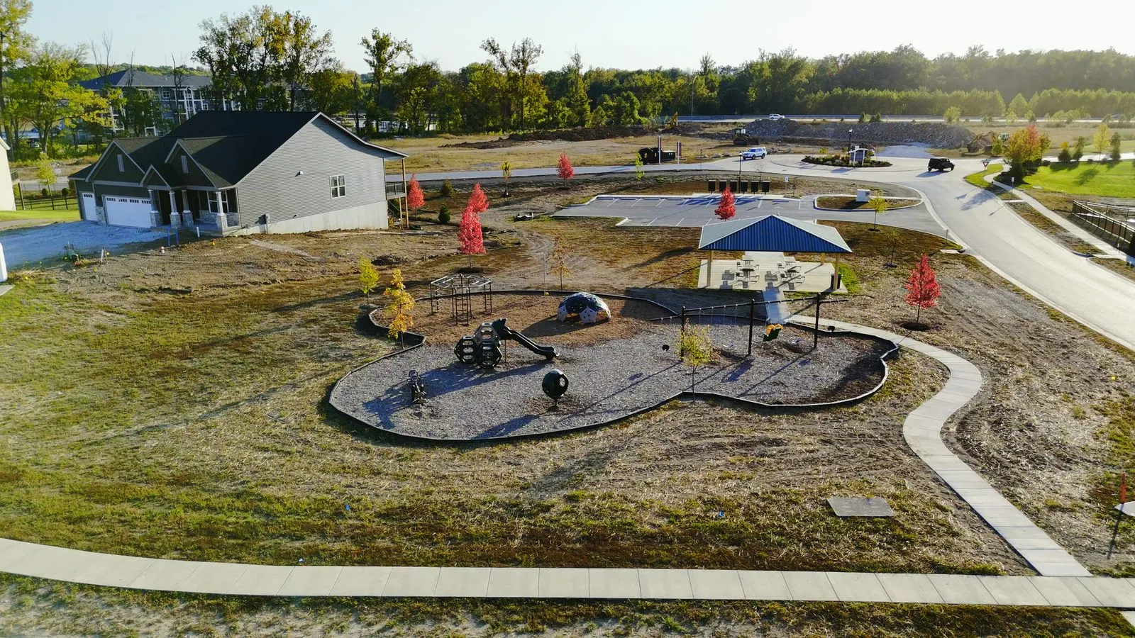 A newly installed playground at Cottleville Trails in October 2025, with play equipment set in fresh mulch and homes lining the street behind it