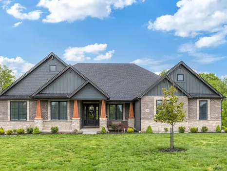 Craftsman new construction home with stone-and-shake gables, brick base, and a manicured front lawn