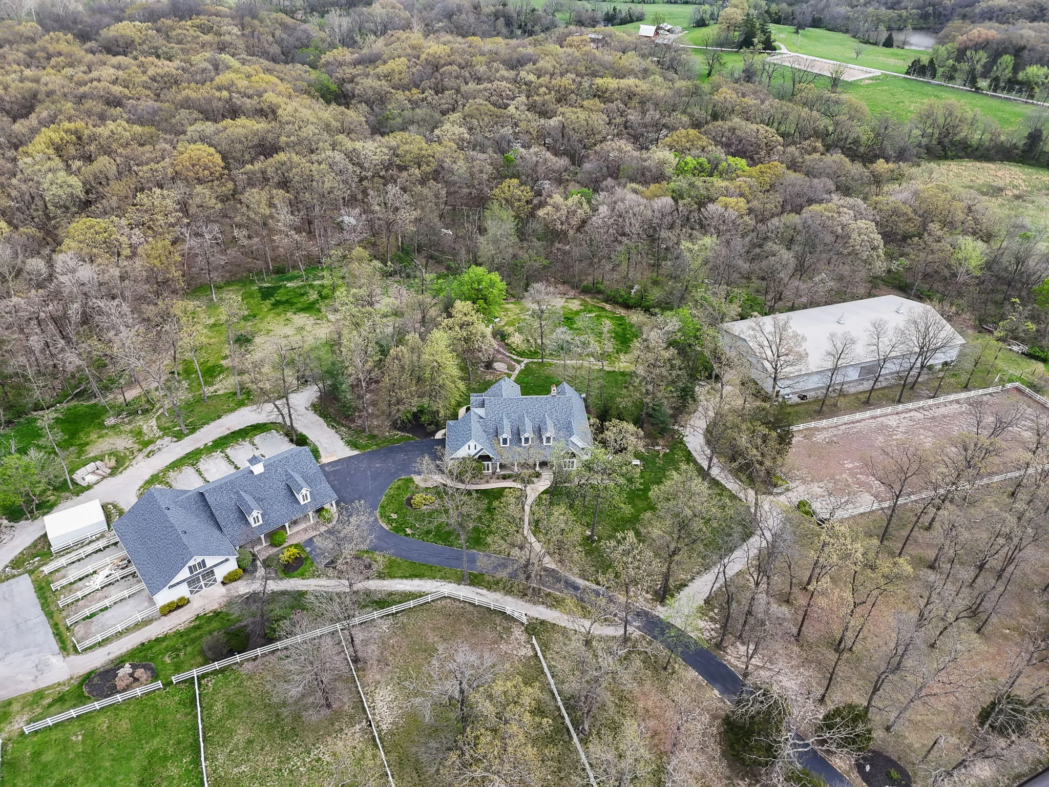 Drone photo showing the wooded grounds, home, outbuildings and riding arena at 1357 Schwede Road