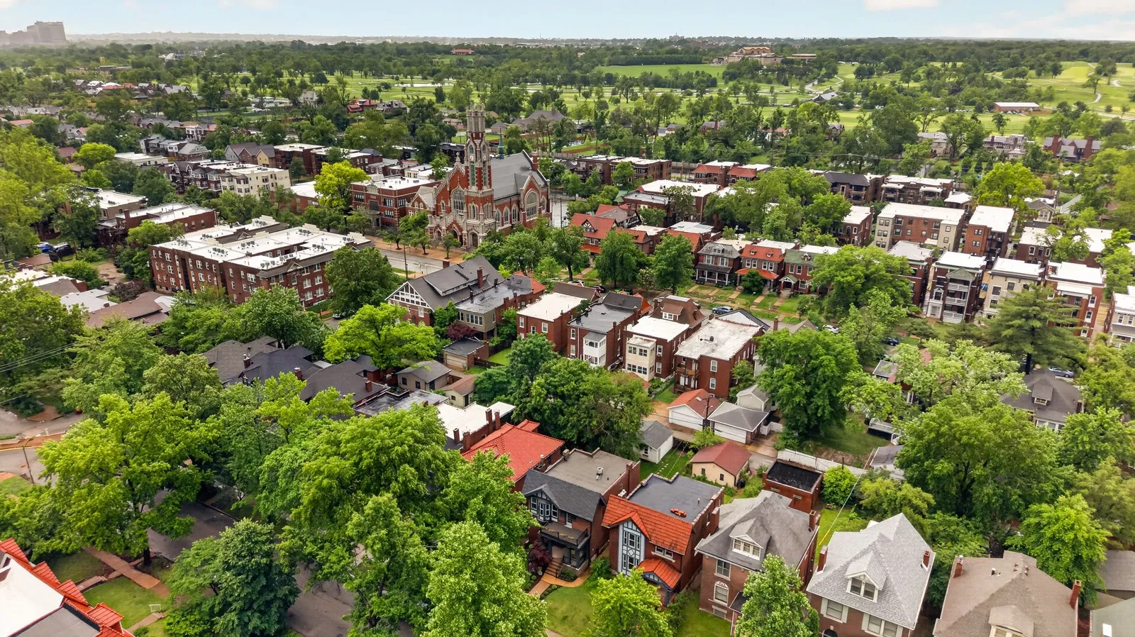 Drone photo over a historic St. Louis city neighborhood of brick homes and a church spire