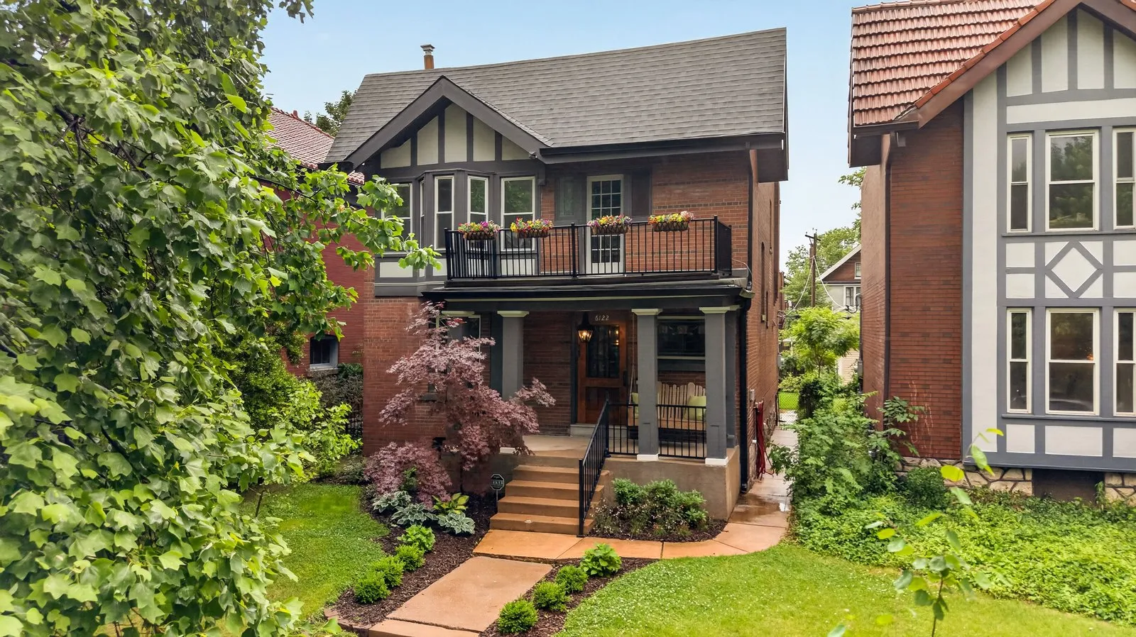 Closer drone photo of the same brick and half-timbered Tudor home and its balcony