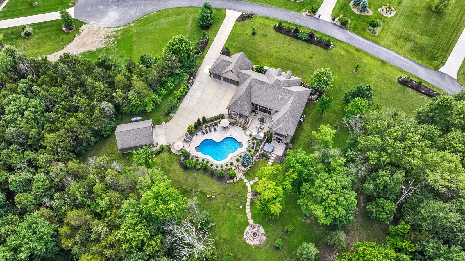 Drone photo of an estate home, its drive and wooded grounds