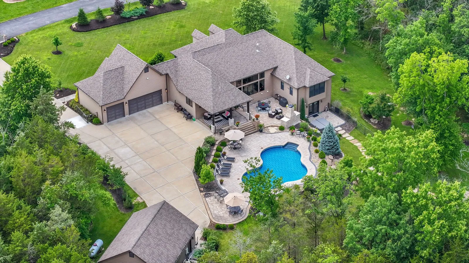 Closer drone photo of the same home's pool, patio and outdoor living space