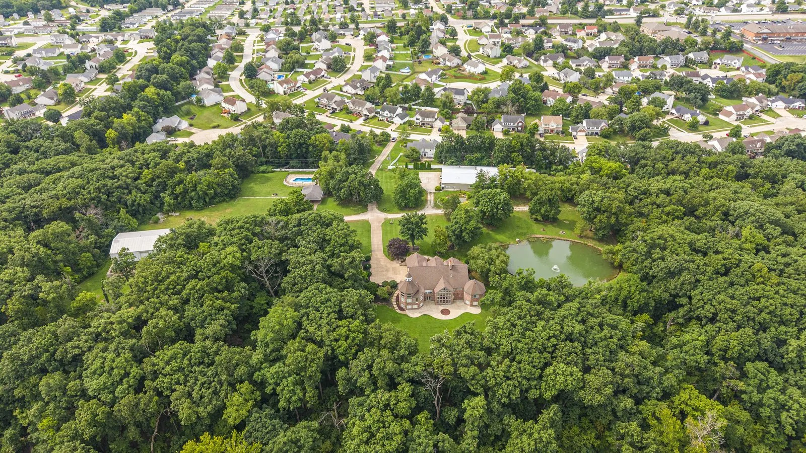 Aerial view of a wooded estate property on acreage listed by Gateway Realty Group