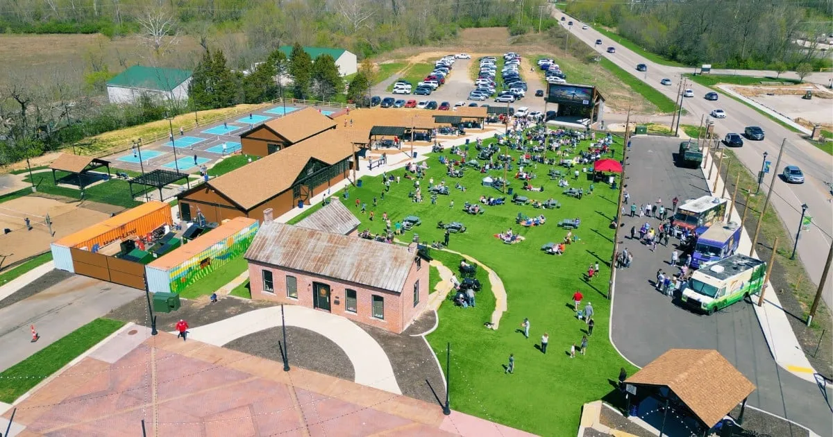 Aerial view of Frankie Martin's Garden in Old Town Cottleville, with the lawn full of people, food trucks along the drive and the pickleball courts