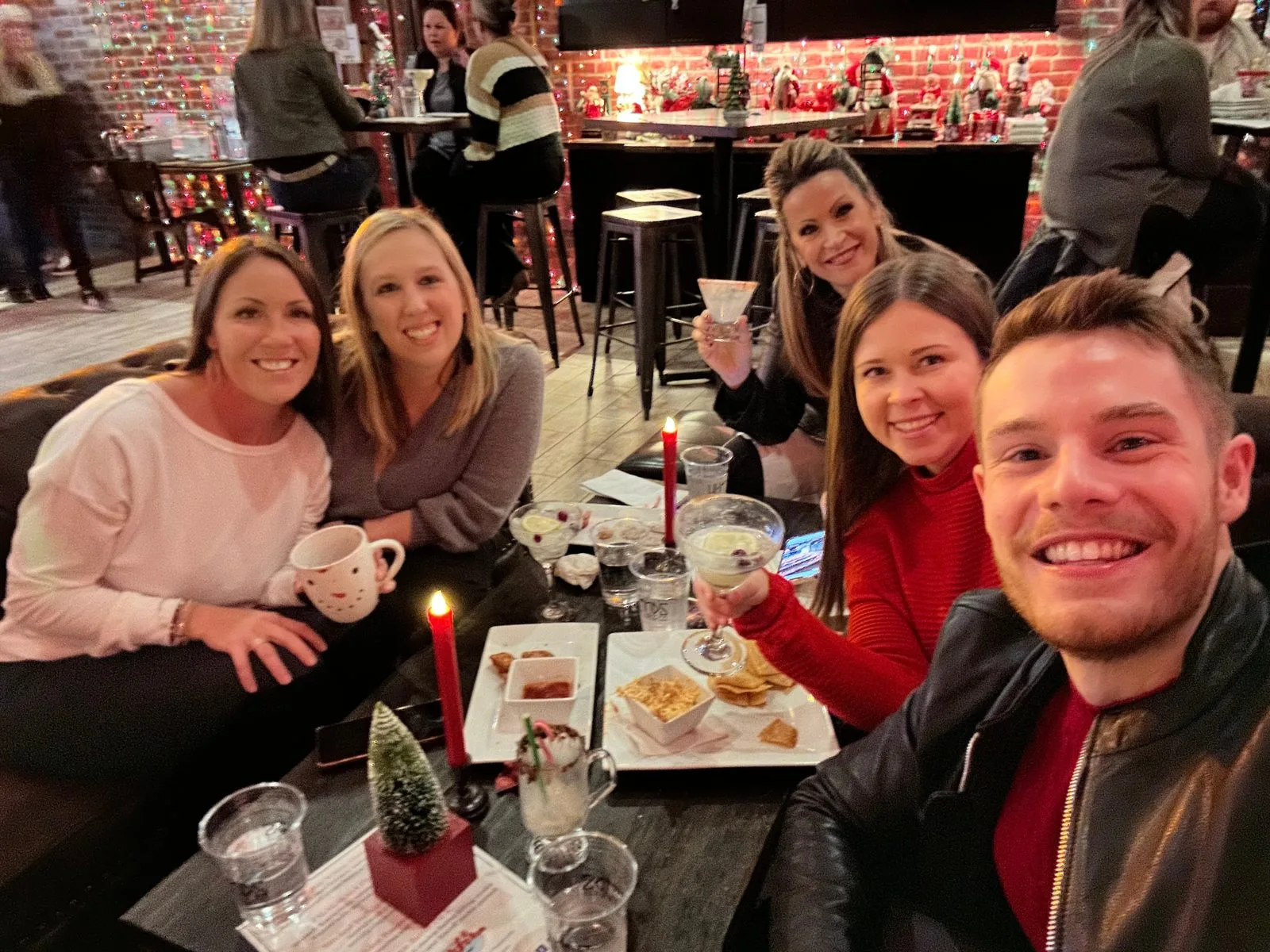 Five Gateway Realty Group team members smiling around a candlelit table at their holiday party at Public School House