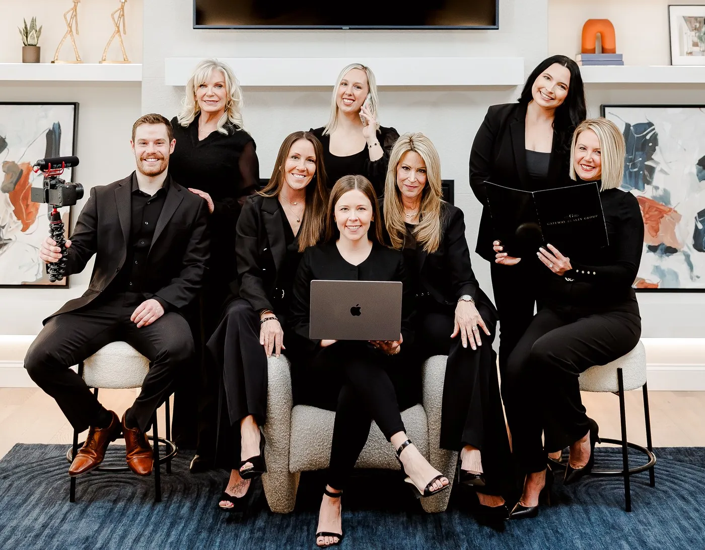 The Gateway Realty Group team together, one holding a camera rig, one a laptop and one a listing presentation