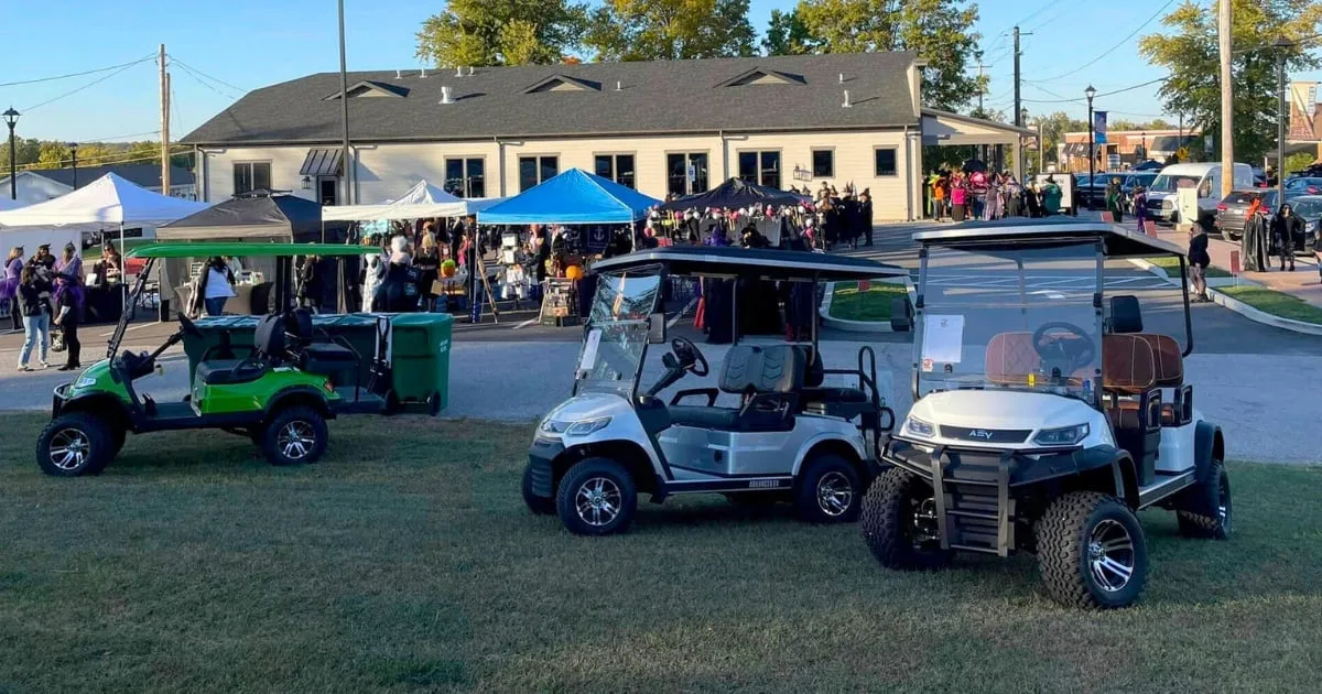 A row of golf carts parked on the grass at an outdoor event in Old Town Cottleville