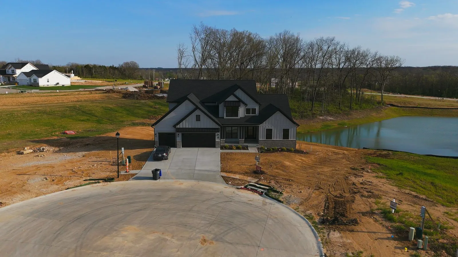 Aerial photograph of a Harvest cul-de-sac in April 2026 with finished homes around it and open graded lots beyond, showing how much of the community is still being built