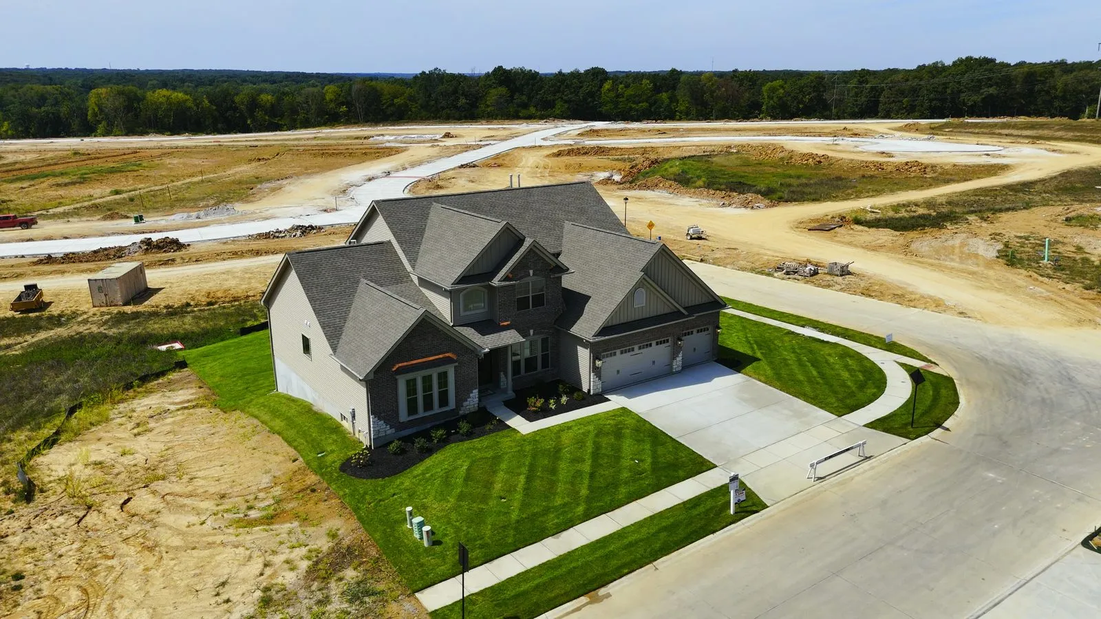 A large Fischer & Frichtel Heritage home at Harvest in August 2025, a brick and stone house with a three-car garage on one of the larger lots at the back of the community