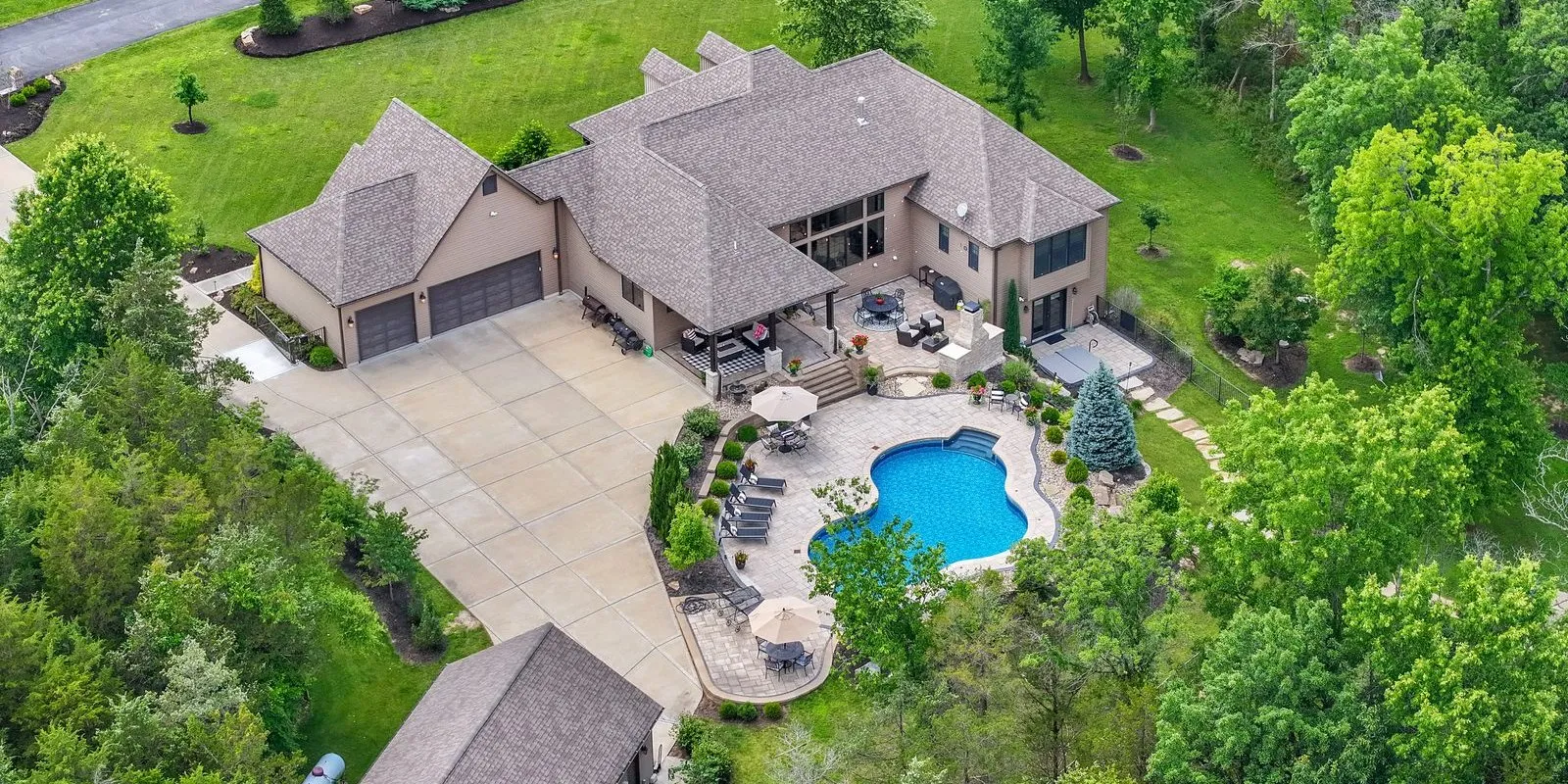 Drone photo of an estate home, its pool and its patio from above