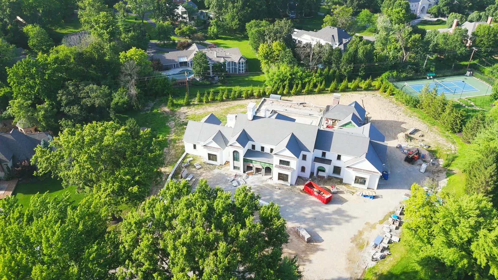 A large custom home under construction on a wooded lot in Huntleigh, Missouri