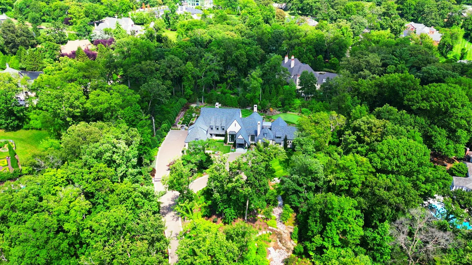 Aerial view of a large custom home surrounded by woods in Huntleigh, Missouri