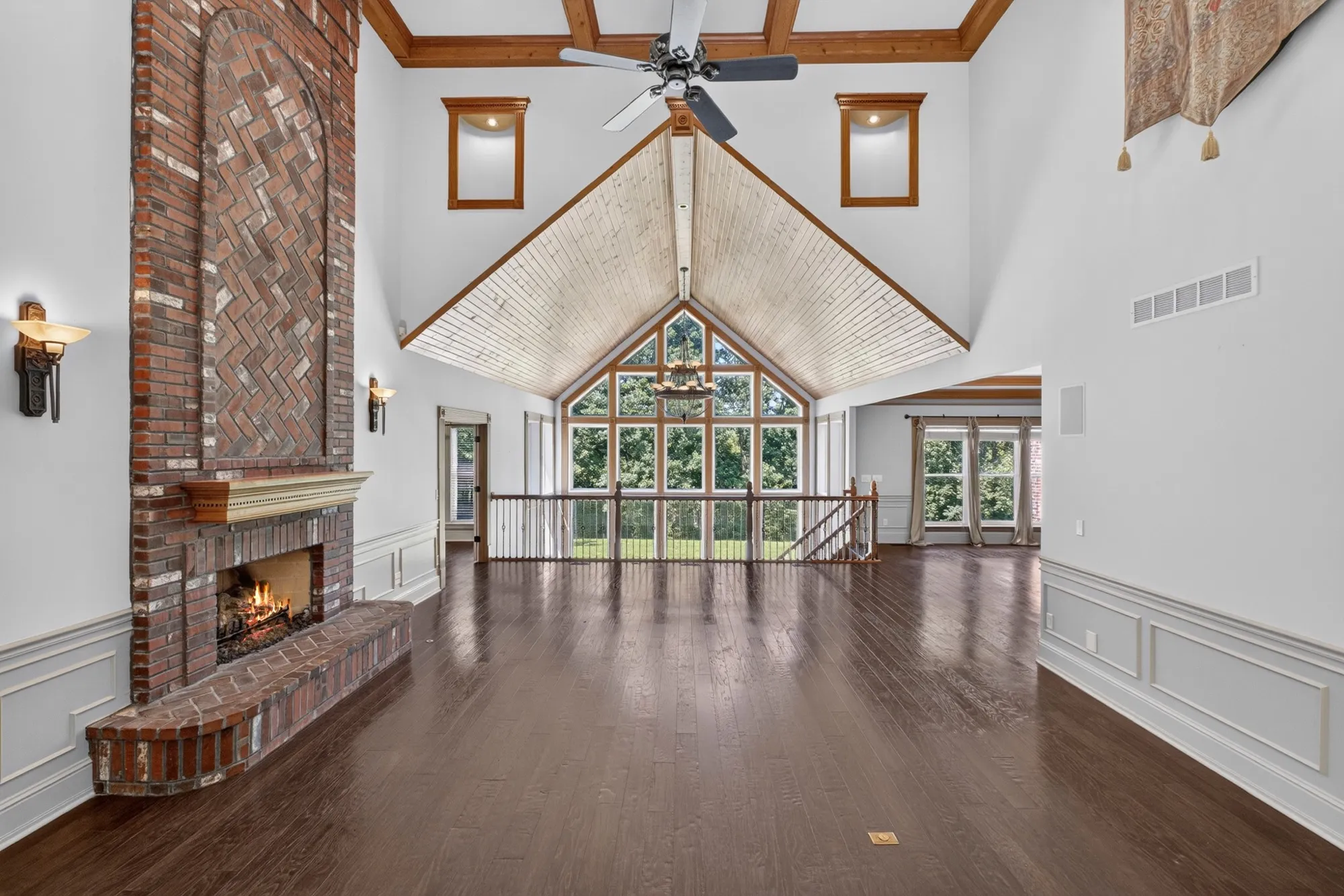 Two-story great room with a herringbone brick fireplace, vaulted wood ceiling and a wall of windows