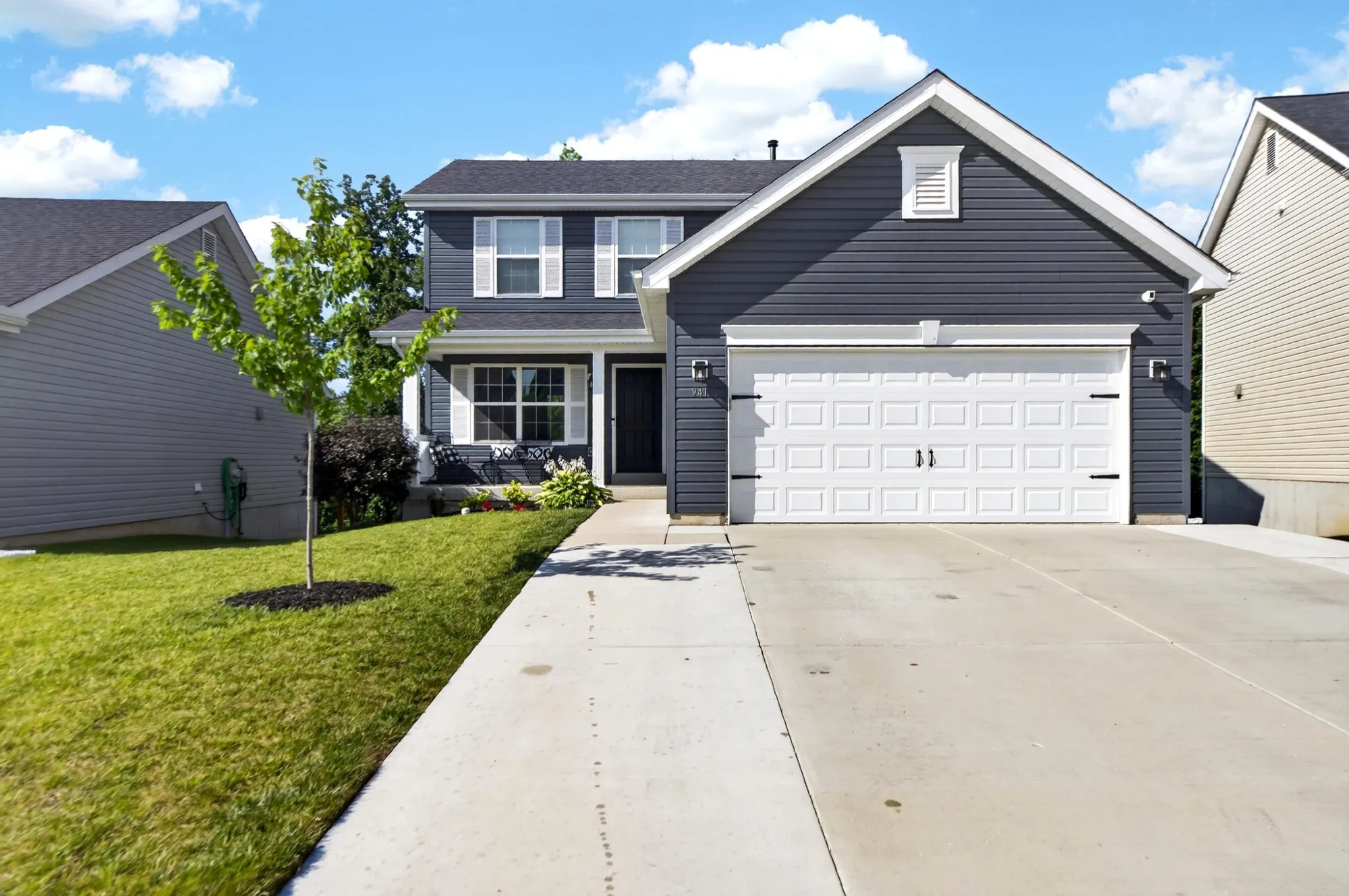 Navy two-story home with white trim and a covered front porch on a sunny street