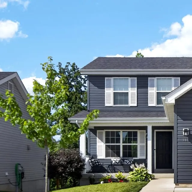 Navy two-story home with white trim and a covered front porch on a sunny street