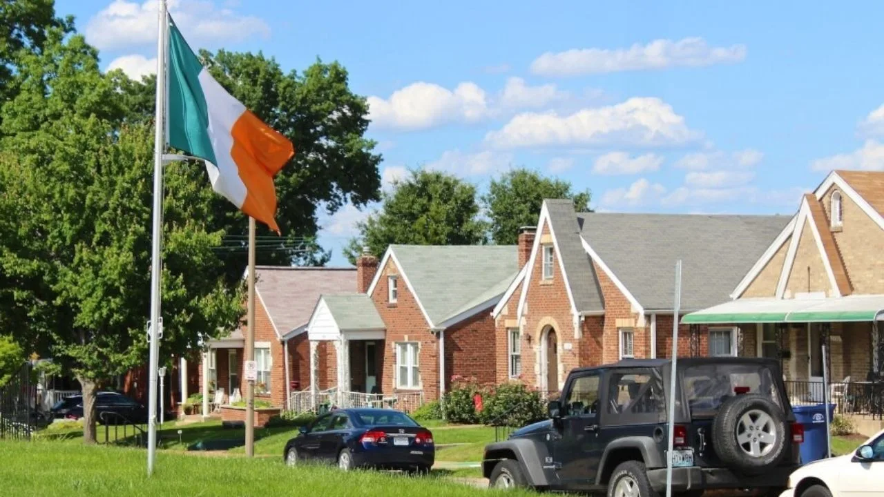 An Irish flag flying above brick bungalows on a residential street in Dogtown, St. Louis