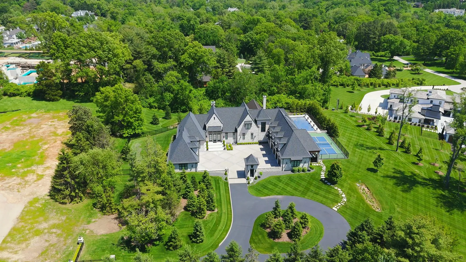 Aerial view of a newer built mansion with a pool and tennis court on a private drive off Litzsinger Road in Ladue, Missouri