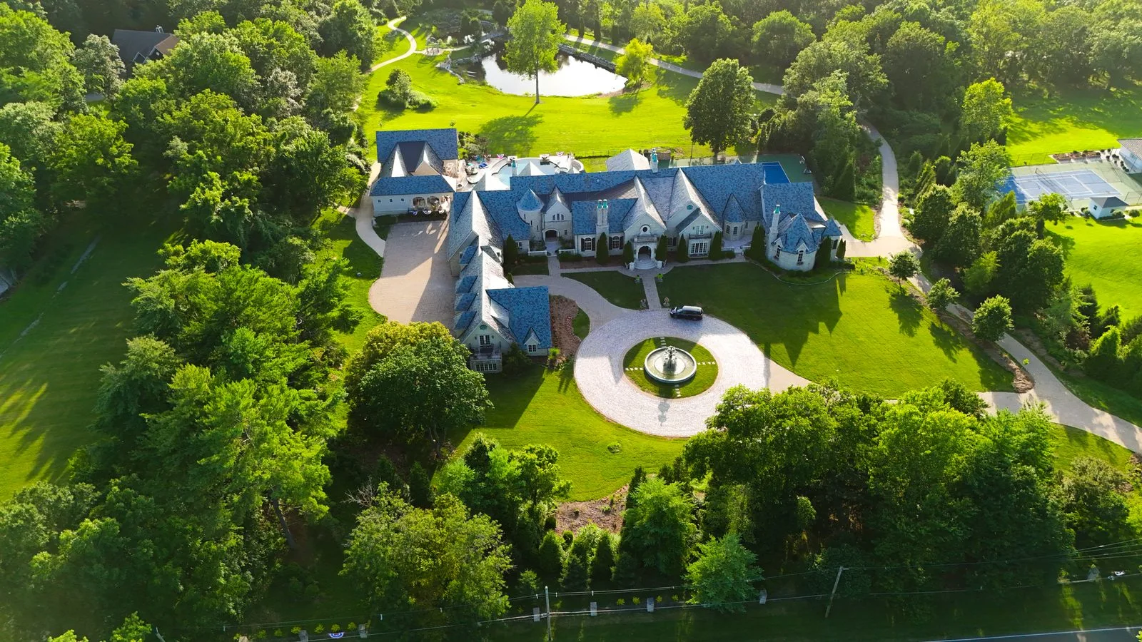 Aerial view of the French-inspired Woodlawn Avenue estate in Ladue, showing its slate roofline, circular drive and wooded grounds