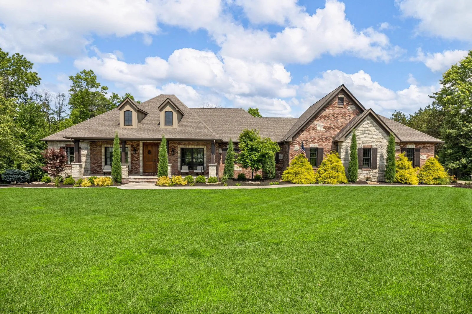 Professionally photographed stone and brick ranch home exterior on a large lawn