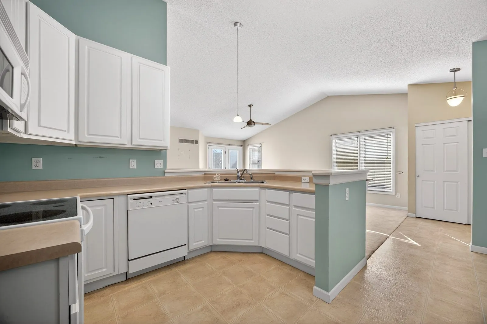 Villa kitchen with white cabinetry, a breakfast bar and a vaulted ceiling beyond