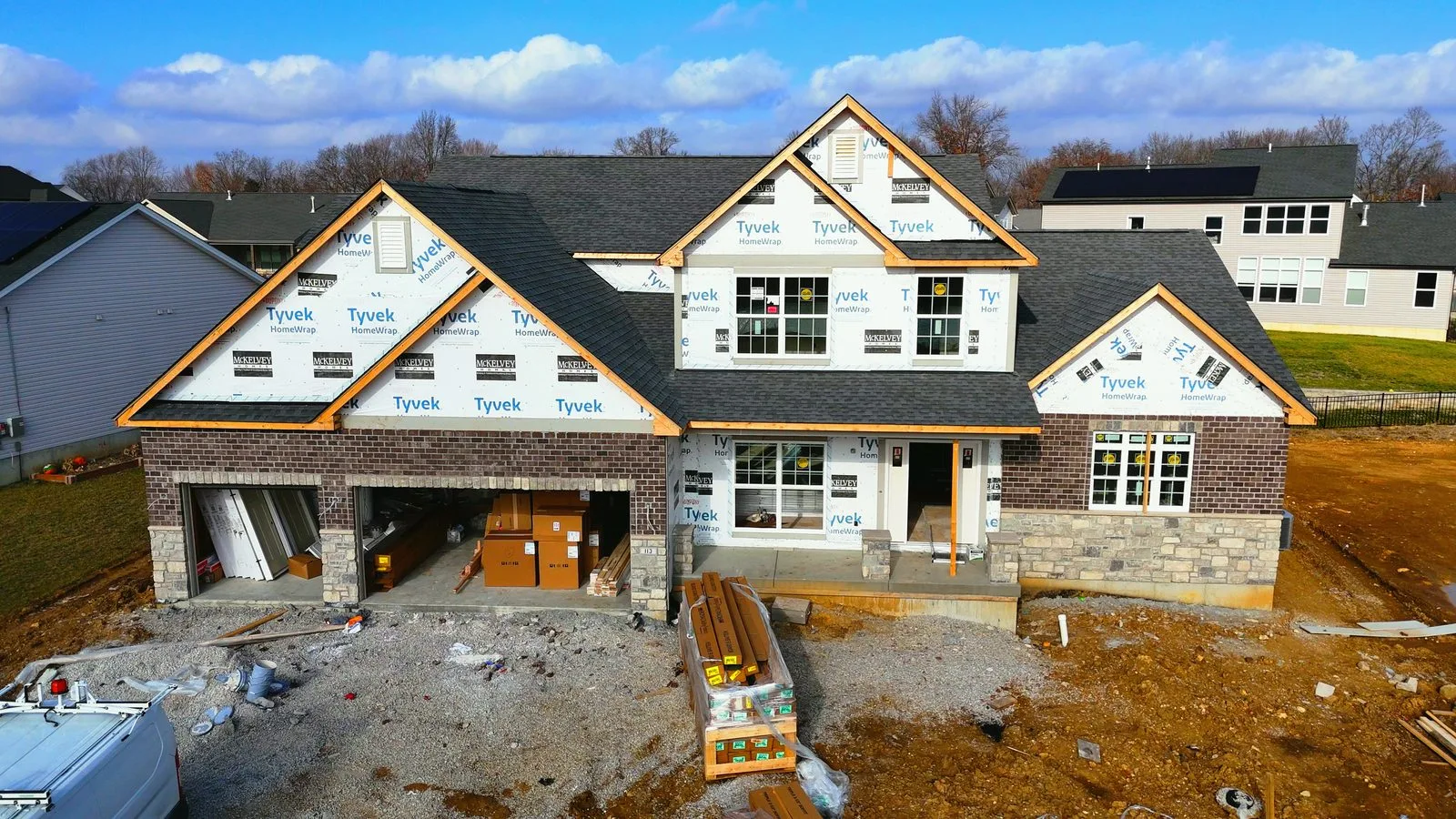 A new construction home in its finishing stages, with brick and siding going on