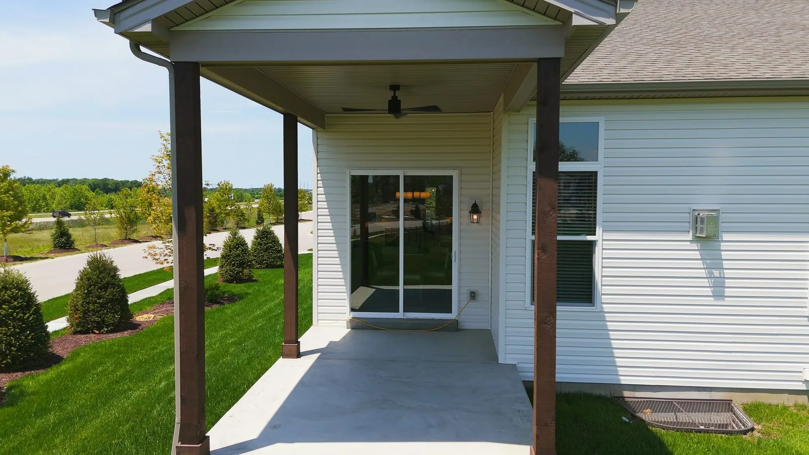 A covered patio with an outdoor ceiling fan on a newly built home