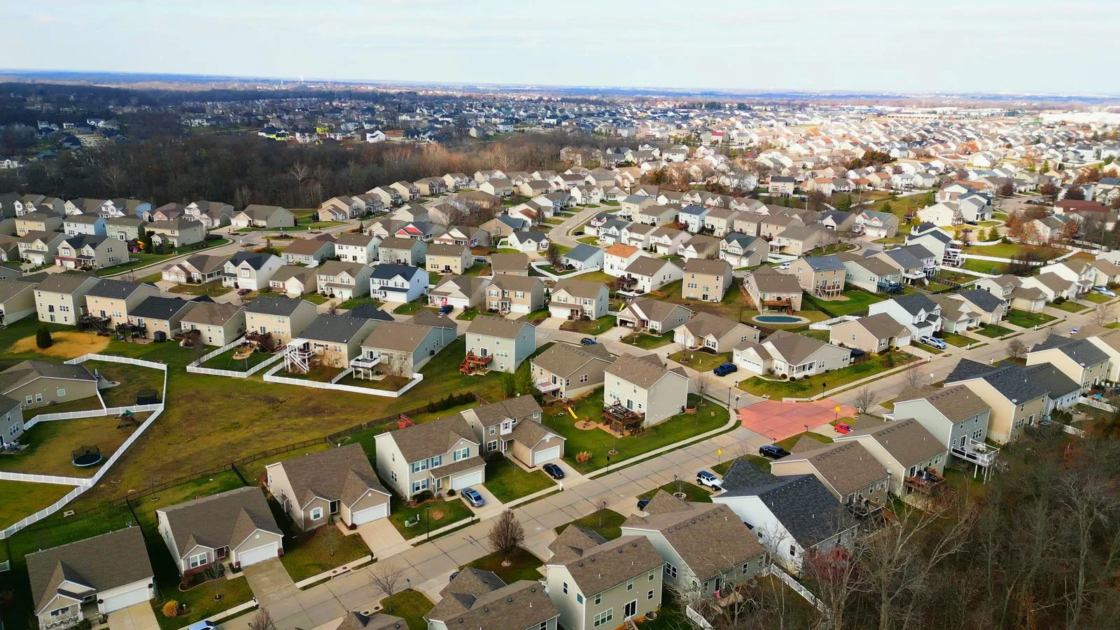 Aerial view over the rooftops of the Preston Woods neighborhood in O'Fallon, MO, with subdivisions stretching to the horizon