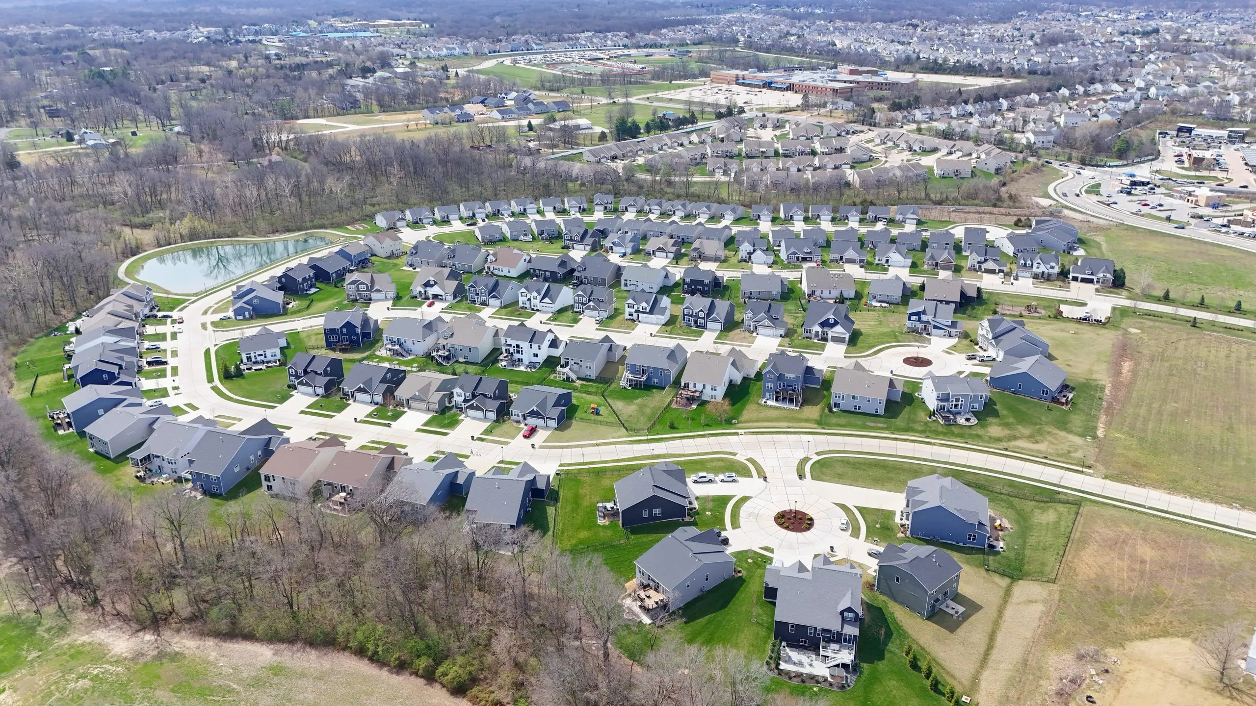 Aerial view of new construction homes around a neighborhood pond in O'Fallon, Missouri
