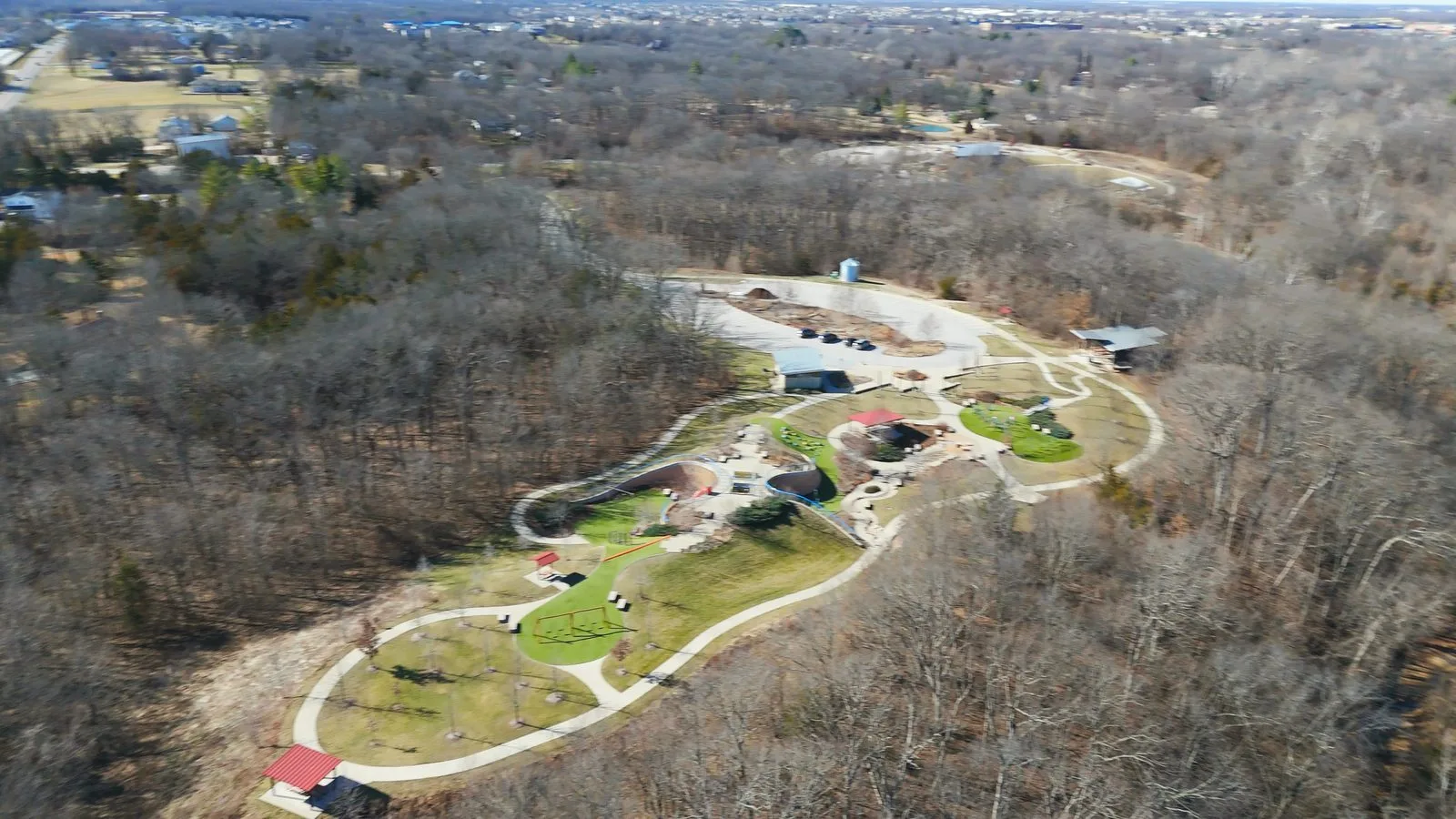 Aerial view of O'Day Park in O'Fallon, MO: a paved walking loop, playground and pavilions surrounded by woods