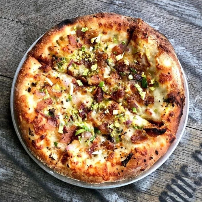 Brussels sprout and bacon pizza on a wooden table at Plank Road Pizza in Cottleville
