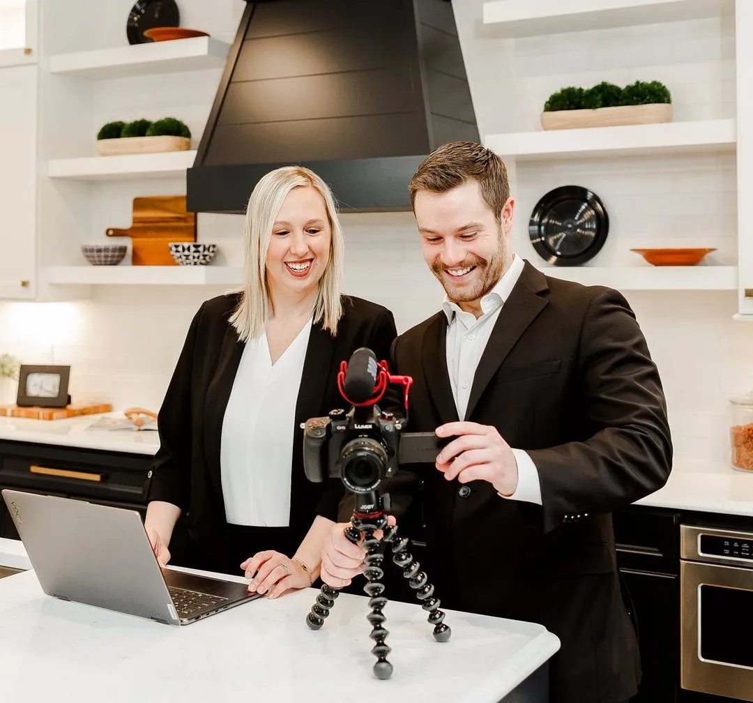 Jacob Peistrup and Kate Wilhelms reviewing listing video footage on a camera and laptop in a client's kitchen