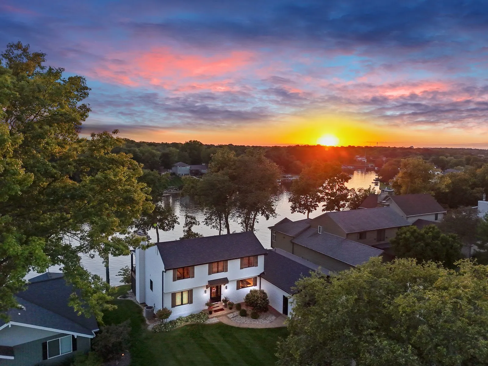 Twilight drone photo of a lakefront home at sunset with the windows lit