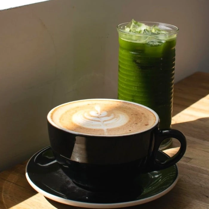 A latte with foam art and a tall iced green juice on the counter at Upshot Coffee in Cottleville