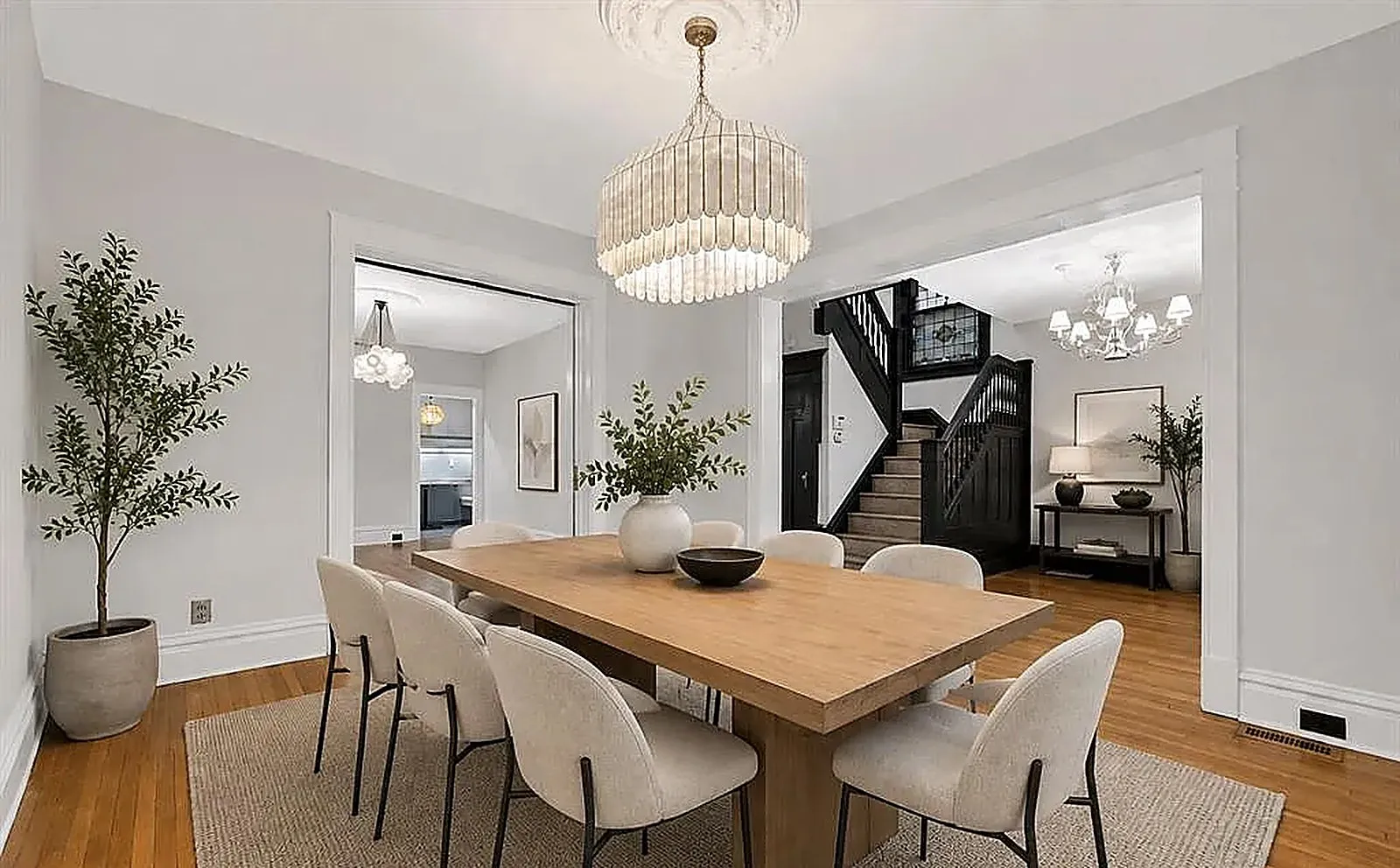 Virtually staged dining room with a wood table, upholstered chairs and plants