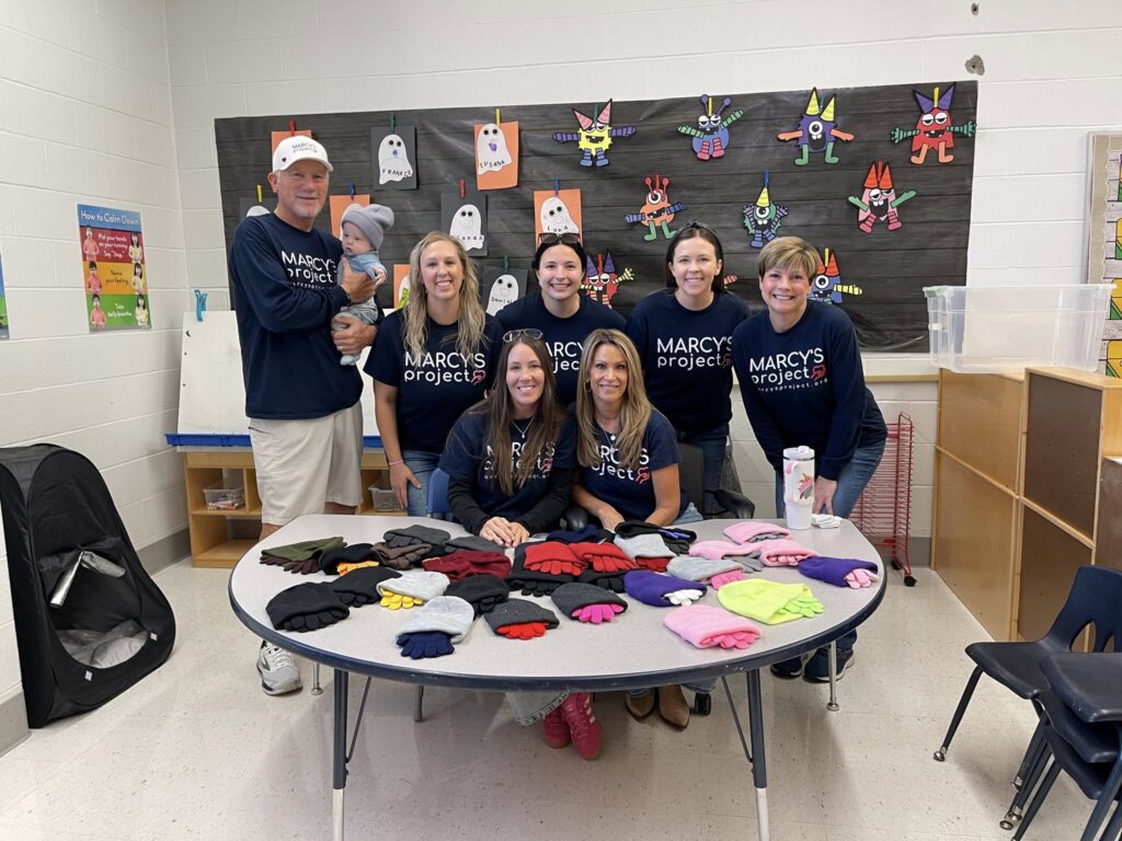 Volunteers stand around a table with hats and gloves